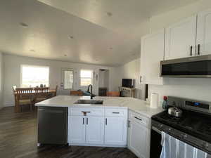 Kitchen featuring sink, kitchen peninsula, white cabinetry, stainless steel appliances, and dark hardwood / wood-style floors