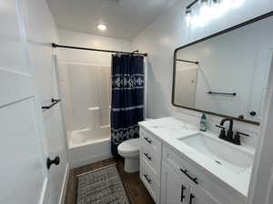 Full bathroom featuring wood-type flooring, a textured ceiling, shower / tub combo with curtain, vanity, and toilet