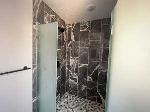 Bathroom featuring a tile shower and a textured ceiling