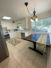 Kitchen with white cabinets, white range, hanging light fixtures, and dishwasher