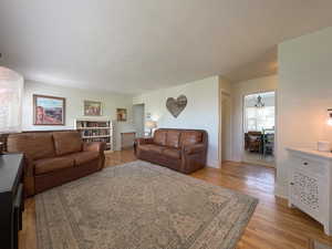 Living room with an inviting chandelier, light hardwood / wood-style floors, and a textured ceiling