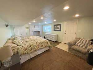 Bedroom featuring light carpet, a textured ceiling, and a brick fireplace