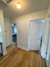 Corridor featuring light wood-type flooring and a textured ceiling