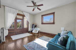 Living room with dark hardwood / wood-style flooring and ceiling fan