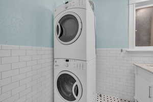 Laundry area featuring tile walls and stacked washing maching and dryer