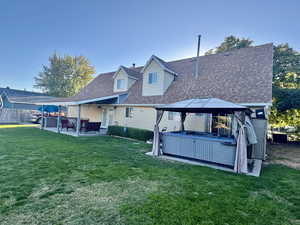 Rear view of property with a gazebo, a yard, a patio, and a hot tub