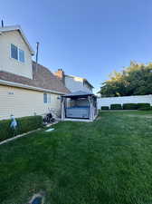 Back of property with a lawn, a gazebo, and a hot tub