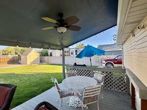 Deck with ceiling fan, a yard, and a shed