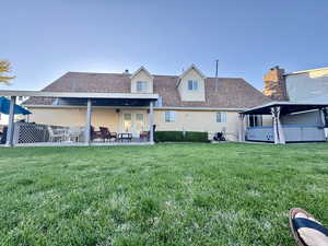 Back of property with a lawn and a patio