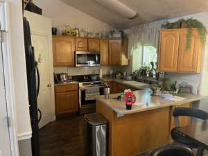 Kitchen featuring a breakfast bar area, kitchen peninsula, appliances with stainless steel finishes, and sink