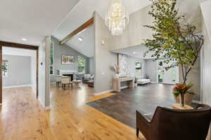 Entrance foyer with a notable chandelier, high vaulted ceiling, beamed ceiling, and hardwood / wood-style flooring