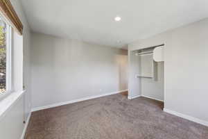 Unfurnished bedroom featuring a closet, carpet flooring, and multiple windows