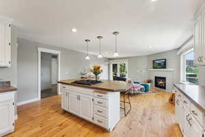 Kitchen featuring light wood-type flooring, a center island, pendant lighting, and white cabinets