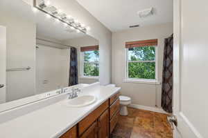 Bathroom featuring walk in shower, vanity, and toilet