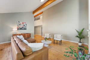 Living room featuring vaulted ceiling with beams and light hardwood / wood-style flooring