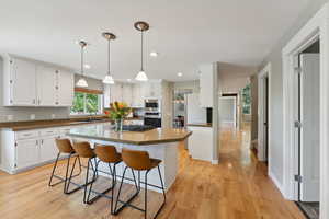 Kitchen featuring a center island, white cabinets, light hardwood / wood-style flooring, a kitchen breakfast bar, and appliances with stainless steel finishes