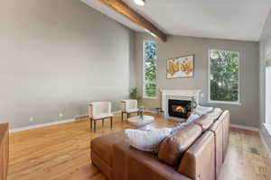 Living room with vaulted ceiling with beams and light hardwood / wood-style floors