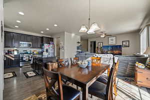 Dining room with ceiling fan with notable chandelier and dark hardwood / wood-style floors