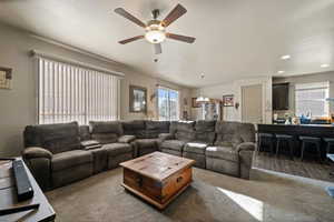 Carpeted living room featuring ceiling fan with notable chandelier