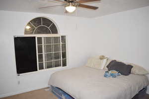 Carpeted bedroom featuring ceiling fan