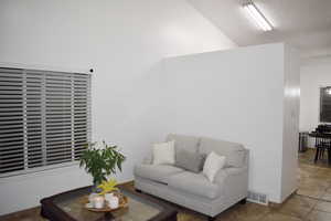 Living room featuring tile patterned flooring and lofted ceiling