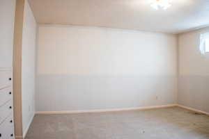 Empty room with light colored carpet and a textured ceiling