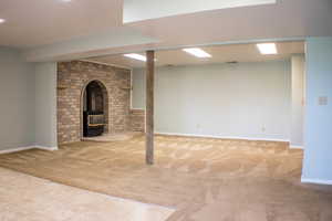 Basement featuring light colored carpet and a wood stove