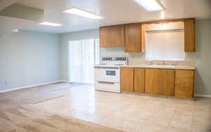 Kitchen featuring sink, electric range, and light colored carpet