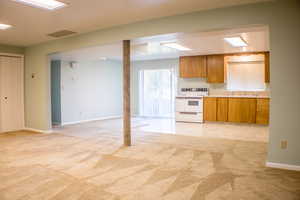 Kitchen with light colored carpet, white electric stove, and sink