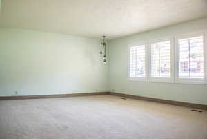 Empty room with a textured ceiling and carpet floors