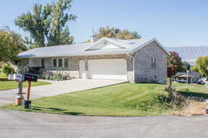 Ranch-style house with a mountain view, a garage, and a front lawn