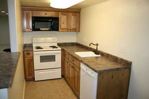 Kitchen featuring white appliances, light tile patterned flooring, and sink