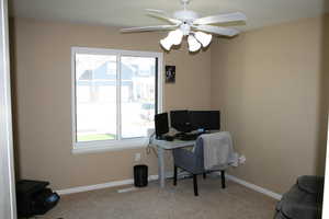 Home office with a wealth of natural light, ceiling fan, and light colored carpet