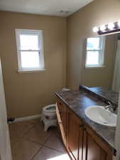 Bathroom with vanity, toilet, and tile patterned floors