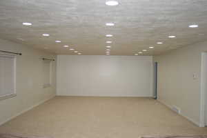 Recreation room with a textured ceiling and light colored carpet