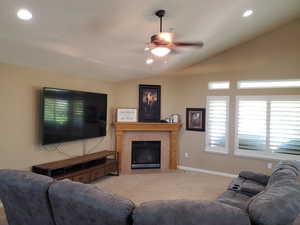 Carpeted living room featuring lofted ceiling and ceiling fan