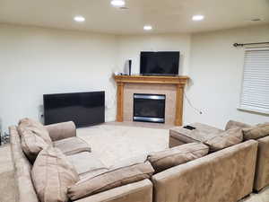 Basement Family Room featuring a tiled fireplace and light carpet