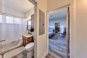 Bathroom with wood-type flooring, vanity, toilet, and electric panel