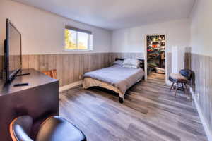 Bedroom with wood-type flooring and wooden walls