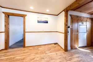 Empty room featuring light wood-type flooring and ornamental molding