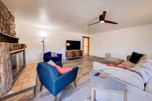 Living room with light wood-type flooring, a fireplace, and ceiling fan