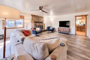 Living room with ceiling fan, hardwood / wood-style flooring, a fireplace, and a healthy amount of sunlight