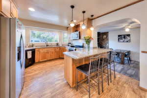 Kitchen featuring a kitchen bar, appliances with stainless steel finishes, kitchen peninsula, and light hardwood / wood-style flooring