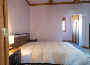 Bedroom featuring light hardwood / wood-style floors, beamed ceiling, and ceiling fan