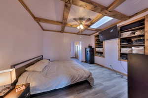 Bedroom with ceiling fan, beamed ceiling, and hardwood / wood-style floors