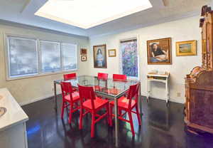 Dining area featuring a raised coffered ceiling, ornamental molding, and dark hardwood / wood flooring