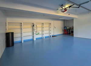 Garage with a garage door opener and finished flooring and a shop area