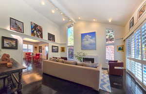 Living room with a towering ceiling and dark wood flooring, featuring a fire place and track lighting