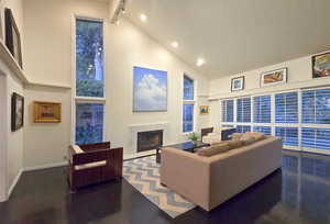 Living room with a towering ceiling and dark wood flooring, featuring a fire place