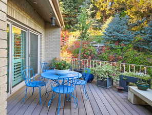 View of front entry wooden deck with sliding glass door entry to level 1, and landscaping